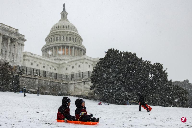 本月16日，美国华盛顿特区细雪纷飞，孩子们在国会大厦旁滑雪橇。（彭博社）