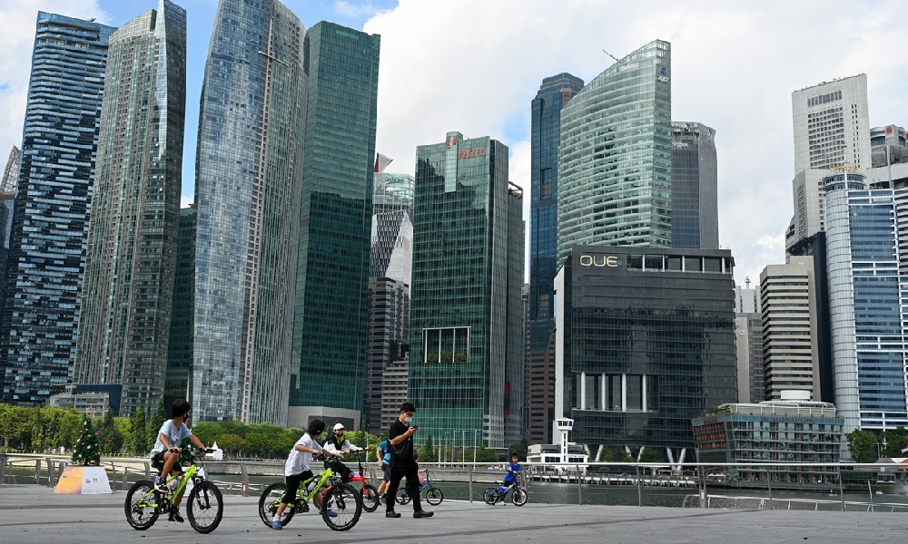 People ride bicycles along the promenade at Marina Bay in Singapore on December 21, 2021. Photo: AFP